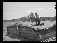 Pie Town, New Mexico. A community settled by about 200 migrant Texas and Oklahoma farmers who filed homestead claims. Faro Caudill taking down the chimney from his dugout before he tears down the dugout by Russell Lee