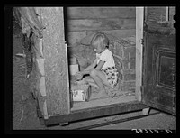 Daughter of homesteader getting chicken feed in slab shed. Trunk seen through the doorway was used to bring personal affects of the family west. Pie Town, New Mexico by Russell Lee