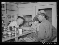Mr. Keele, merchant and president of the Farm Bureau, making out bill for a farmer. Pie Town, New Mexico by Russell Lee