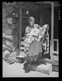 Mrs. Bill Stagg exhibiting a quilt made from tobacco sacks which she ripped up, dyed, and pierced. Nothing is wasted on these homesteading farms. Pie Town, New Mexico by Russell Lee