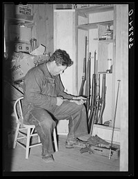 [Untitled photo, possibly related to: George Hutton Jr. looking over his guns. Pie Town, New Mexico] by Russell Lee