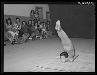 Spanish-American acrobat of traveling show. Audience in background.  Penasco, New Mexico by Russell Lee