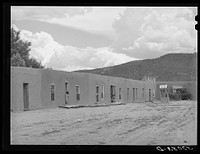 Row of adobe dwellings in Costilla, New Mexico. Well in square supplies several families with water by Russell Lee