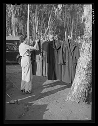 [Untitled photo, possibly related to: Carpenter's wife hanging up coat to dry. Mission Valley, California, which is about three miles from San Diego. This family is living in a tent because of inability to find suitable housing. A heavy rain the night before had everything wet in their tent] by Russell Lee