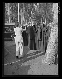 Carpenter's wife hanging up coat to dry. Mission Valley, California, which is about three miles from San Diego. This family is living in a tent because of inability to find suitable housing. A heavy rain the night before had everything wet in their tent by Russell Lee