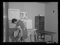 Wife of farmer living at the Yuba City FSA (Farm Security Administration) farm workers' camp. Yuba City, California. She is sewing and pressing in the community building by Russell Lee