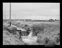 Irrigation ditch and gate with the Free family farmstead in the background. This family is a FSA (Farm Security Administration) rehabilitation borrower. Dead Ox Flat, Malheur County, Oregon by Russell Lee