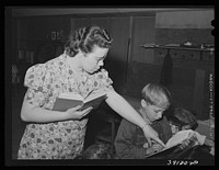 Teacher helps pupil with his reading, FSA (Farm Security Administration) camp for farm workers. Caldwell, Idaho. School is held at the camp because of lack of room in city schools by Russell Lee