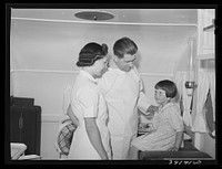 Doctor and nurse with little girl in trailer-clinic at the FSA (Farm Security Administration) migratory labor camp mobile unit. Wilder, Idaho by Russell Lee