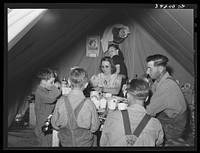 Farm worker's family eating dinner in the tent in which they live at the FSA (Farm Security Administration) migratory labor camp mobile unit. Wilder, Idaho by Russell Lee