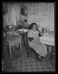 Mexican woman at table in kitchen of her two-room house. San Diego, California by Russell Lee