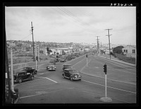 Traffic moving out of town on main highway when Consolidated Aircrafts changes shift in the afternoon. San Diego, California by Russell Lee