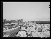 Lumber for construction work stacked in the open along Pacific Highway. San Diego, California by Russell Lee