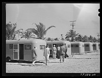 [Untitled photo, possibly related to: Family moving into trailer at the FSA (Farm Security Administration) camp for defense workers. This family is from Minnesota. The man came to San Diego ten months ago and enrolled in a vocational school. He started to work at Consolidated Aircrafts as a riveter and is now a clerk in the machine shop. Before his family came out three weeks ago he lived in a cabin for which he paid twelve dollars per month. He said it was alright for a man but that he wouldn't take his wife and children into such a place. He got a furnished apartment for his family--it was two rooms, rental eleven dollars per week. His wife soon discovered that there was inadequate hot water and was overrun with roaches and rats. San Diego, California] by Russell Lee