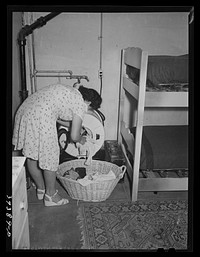 Room for maids who work in boarding house for single men who are mostly employed at the Consolidated Aircrafts. Notice the laundry tub in same room. The maids are paid five dollars per week and room and board. San Diego, California by Russell Lee