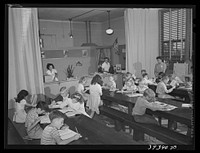 Second and third grades at the Balboa School, San Diego, attend classes held in the cafeteria of the school. San Diego, California by Russell Lee