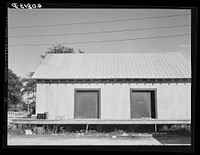 Warehouse that provides housing for a number of migratory agricultural workers. On the left is the baggage of some of the new arrivals. Camden, North Carolina. Sourced from the Library of Congress.
