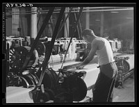 At a loom in the Denomah Mills, Taftville, Connecticut. Makers of rayon and cotton cloths. Sourced from the Library of Congress.