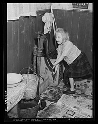 Daughter of a worker at the Pittsburgh Crucible Steel Corporation of Midland, Pennsylvania. Her father is at present in bed as a result of a leg injury at the mill. There are seven children and they help out by selling magazines from door to door. The pump is the only source of water. Sourced from the Library of Congress.