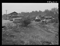 Part of a trailer camp for migratory workers, employed at Fort Bragg, North Carolina. Trailer space is one dollar a week, and small bunk houses five dollars a week. One water spigot near the general store serves the whole camp until 6 p.m. On the left is an old trolley car used as living quarters by a small family who came one hundred miles to work at the Fort. Some of the families here came from Texas, Idaho, Georgia, South Carolina and other parts of North Carolina twelve miles from Fayetteville, North Carolina (Manchester). Sourced from the Library of Congress.