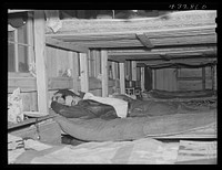 Man who works at Fort Bragg, North Carolina sleeping in a bunk house recently built to house thirty or forty men. There were only a few men left, most of them having been laid off had left. A few miles out of Fayetteville, North Carolina. Sourced from the Library of Congress.