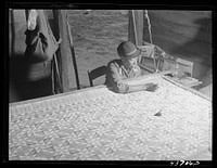 [Untitled photo, related to: A woman who has not yet found a place to move out of the Hinesville Army camp area working on a quilt in her smokehouse. Near Hinesville, Georgia]. Sourced from the Library of Congress.