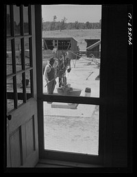 Screen door at the home of tenant purchase client Robert McKiver. Showing FSA (Farm Security Administration) pump in back. Woodville, Greene County, Georgia. Sourced from the Library of Congress.