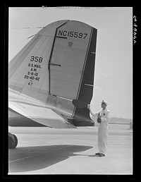 A ground crew assistant removing the block from the rudder preparatory to the plane's taking off. Municipal airport, Washington, D.C.. Sourced from the Library of Congress.