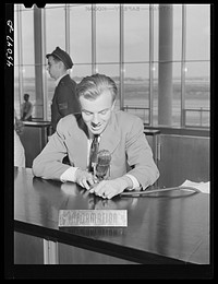 The C.A.A. announcer. He speaks from the central information desk and his voice is heard thru loudspeakers in every corner of the building and on the field. Municipal airport, Washington, D.C.. Sourced from the Library of Congress.