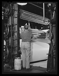 Starting a new roll of paper at the receiving end of the large rolling machine. At the Mississquoi Corporation paper mill. Sheldon Springs, Vermont. Sourced from the Library of Congress.