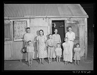 [Untitled photo, possibly related to: French village, a small settlement on Saint Thomas Island, Virgin Islands. French family living in one of the tiny houses in the French village, a small settlement. Several of the children suffer from an eye disease that necessitates a delicate operation possible only in the United States]. Sourced from the Library of Congress.
