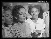 Guanica, Puerto Rico (vicinity). At a Three Kings' eve party in the home of a farm laborer's family. The woman is serving "pastellas" [i.e. pasteles], a tamale-like dish made with plantain. Sourced from the Library of Congress.