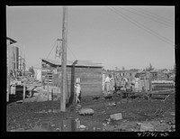 San Juan, Puerto Rico. Fetching water from a spigot which services many people in the huge slum area known as "El Fangitto" ("the mud"). The people must wade through the mud to get to the water spigot. Sourced from the Library of Congress.