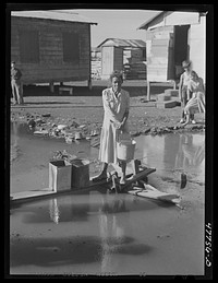 San Juan, Puerto Rico. Fetching water from a spigot which services people who live in the huge slum area known as "El Fangitto". Sourced from the Library of Congress.