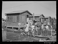 San Juan, Puerto Rico. Fetching water from a spigot which services many people who live in the huge slum area known as "El Fangitto" ("the mud"). Sourced from the Library of Congress.