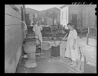 [Untitled photo, possibly related to: San Juan, Puerto Rico. Washing clothes in a back yard in El Fangitto, a slum area]. Sourced from the Library of Congress.