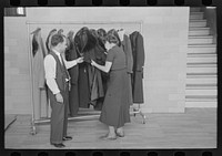 Sam Schultz shows a model coat to a perspective customer at the cooperative garment factory, Jersey Homesteads by Russell Lee