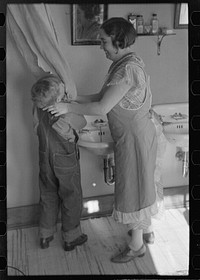Mrs. Rustan combing her young son's hair. Rustan brothers' farm, Dickens, Iowa. Note running water by Russell Lee