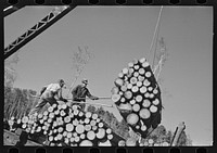 Loaders pushing logs into place while loading car, lumbercamp near Effie, Minnesota by Russell Lee