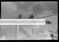 [Untitled photo, possibly related to: Barn erection. Sliding last half of one gable end into place. Note that gable end sheathing overlaps sheathing of wall panels, forming a drip. Southeast Missouri Farms Project] by Russell Lee
