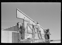 Barn erection. Gable panel at corn crib end is raised into place and nailed. Southeast Missouri Farms Project by Russell Lee