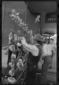Concessionaire placing doll canes in rack, National Rice Festival, Crowley, Louisiana by Russell Lee