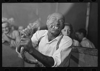 Man chewing piece of snake which he has just bitten off, state fair sideshow, Donaldsonville, Louisiana by Russell Lee