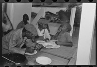  stevedores eating on stern of boat. Food supplied to crew consists almost entirely of carbohydrates with some of the cheaper cuts of meat. Sleeping quarters are not provided for stevedores, who sleep in any available space by Russell Lee