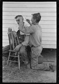 [Untitled photo, possibly related to: Cajun sugarcane farmer cutting hair of neighboring farmer near New Iberia, Louisiana] by Russell Lee