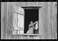 Wife of FSA (Farm Security Administration) client near Morganza, Louisiana removing bag of food from nail by Russell Lee