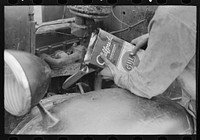 Migrant worker pouring oil into motor of automobile near Harlingen, Texas by Russell Lee