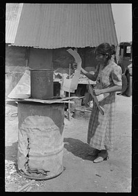 [Untitled photo, possibly related to: Mexican woman building fire in battered steel drum in backyard of her house, San Antonio, Texas] by Russell Lee