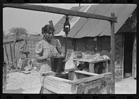 [Untitled photo, possibly related to: Mexican woman drawing a bucket of water from backyard well, San Antonio, Texas] by Russell Lee