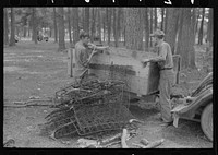 [Untitled photo, possibly related to: White migrant strawberry picker unloading automobile cushion springs from trailer. These will be used as bed springs. Hammond, Louisiana] by Russell Lee